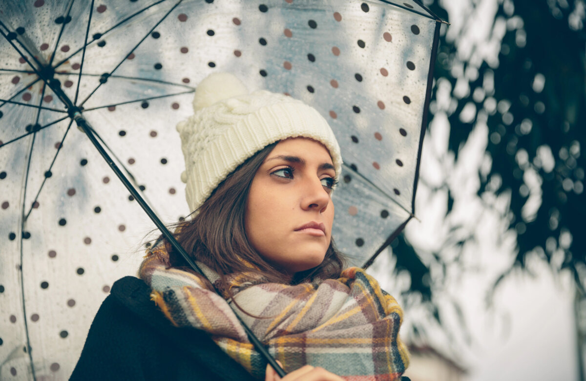 young girl holding umbrella in an autumn rainy day